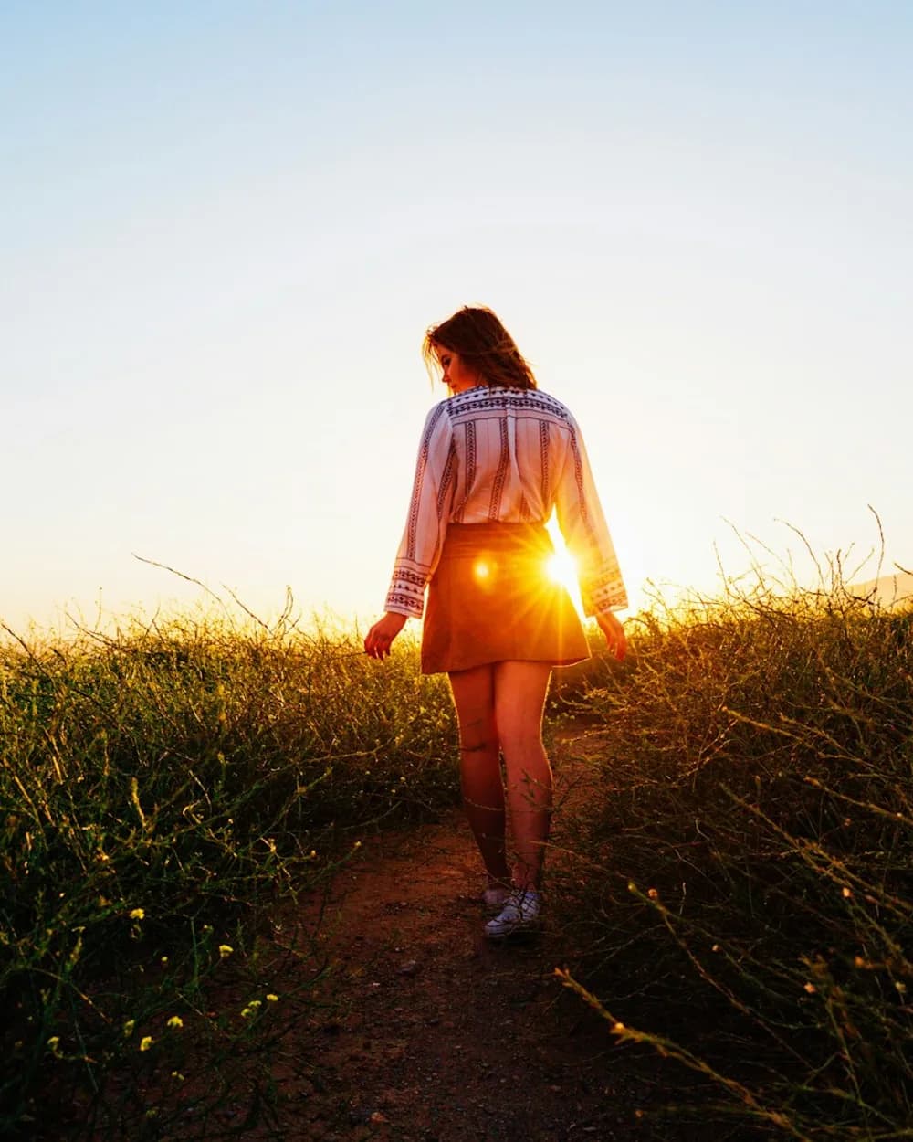 Woman walking through a sunlit field in the morning