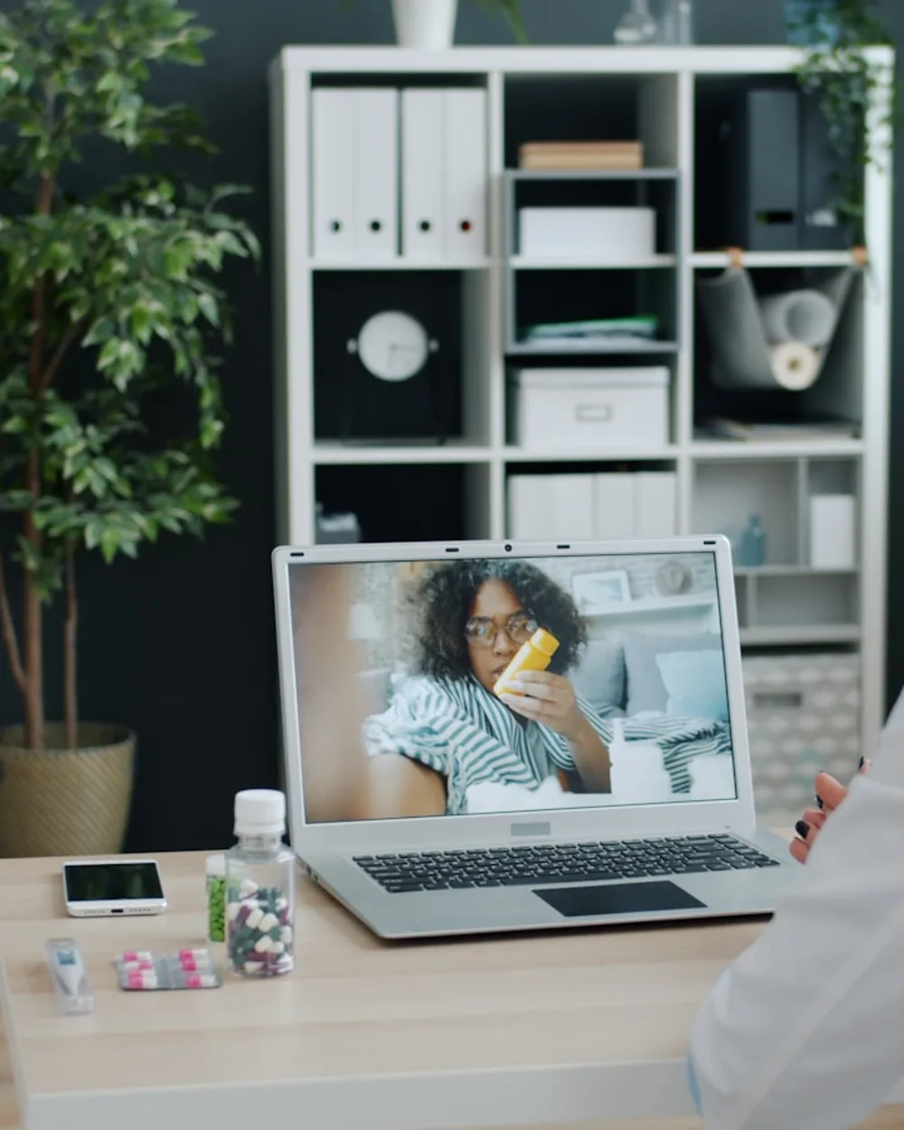 Laptop on a home desk showing a doctor during a telehealth video visit
